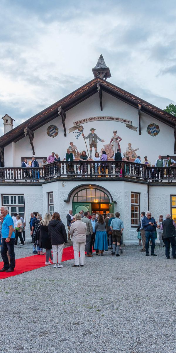 Besucher des Bauerntheaters in Schliersee warten vor dem historischen Gebäude auf den Einlass zur Theateraufführung