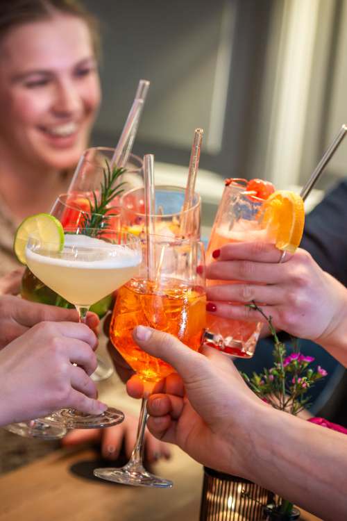 Gäste in der Xaver Bar in Schliersee stoßen mit Cocktails und Longdrinks an